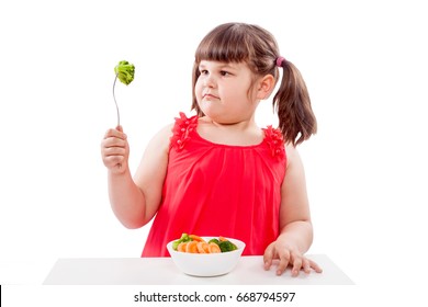 How to teach children to eat healthy food. Girl eats broccoli, sits with plate of food isolated on white background