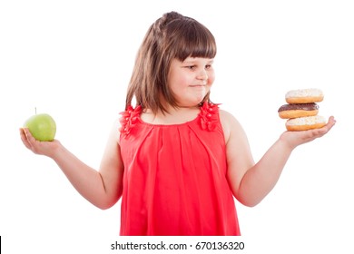 How to teach children to eat healthy food. Girl chooses what to  eat donuts or fresh apple, isolated on white background - 3