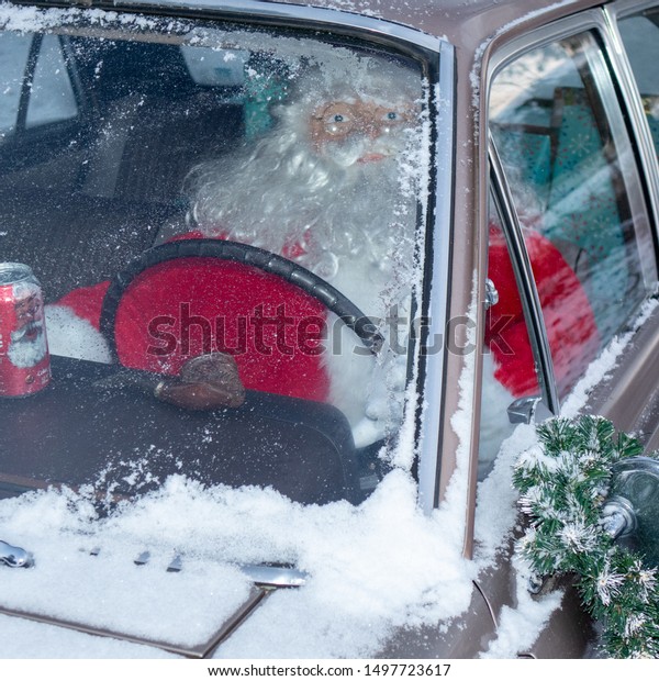 Howell, Michigan/
USA - December 2017:  Snowy car with (mannequin) Santa driving,
seen from front of
automobile.