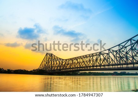 Howrah bridge - The historic cantilever bridge on the river Hooghly in West Bengal with twilight sky. Beautiful sunset view with blue sky and clouds.