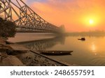 Howrah bridge with wooden boats on the Ganges river at sunrise at Kolkata, India. 