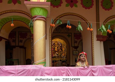 Howrah,India -October 26th,2020 : Bengali Girl Child In Festive Dress, Smiling And Posing With Goddess Durga In Background, Inside Old Age Decorated Home. Durga Puja, Biggest Festival Of Hinduism.