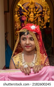 Howrah,India -October 26th,2020 : Bengali Girl Child In Festive Dress, Smiling And Posing With Goddess Durga In Background, Inside Old Age Decorated Home. Durga Puja, Biggest Festival Of Hinduism.