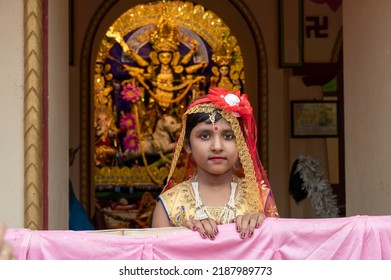 Howrah,India -October 26th,2020 : Bengali Girl Child In Festive Dress, Smiling And Posing With Goddess Durga In Background, Inside Old Age Decorated Home. Durga Puja, Biggest Festival Of Hinduism.