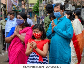 Howrah,WestBengal,India - 25th October 2020 : Masked Hindu Bengali family devotees uttering Sanskrit shlokas for praying to Goddess Durga. Ashtami morning, Durga puja festival in Coronavirus pandemic.