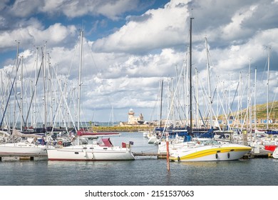 Howth lighthouse seen through masts of sailboats, yachts and motorboats moored in Howth marina, Dublin, Ireland