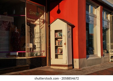 Hoya, Germany - October 10, 2021: Public Bookcase For Borrowing And Exchanging Used Books Free Of Charge Next To A Store In The City Center