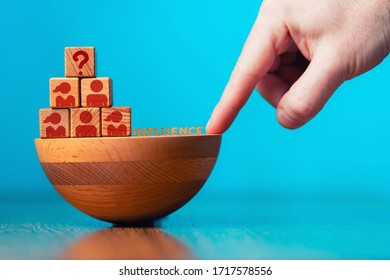 HR Management And Recruitment Business Concept. The Hand Points To The Shaky Foundation Of The Pyramid. Top Cube Block With Sign Of Question. Copy Space. Blue Background