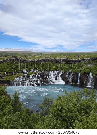 Hraunfossar waterfall with numerous small cascades flowing from a moss-covered lava field into a turquoise river, Iceland