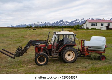 Hrisey, Iceland - July 22, 2010: Farmer On A Tractor Wrapping Hey Bales