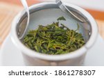 Huang Shan Mao Feng, fresh green tea leaves, spring harvest. From Anhui mountain in China. Close up of wet leaves in a teapot metal filter