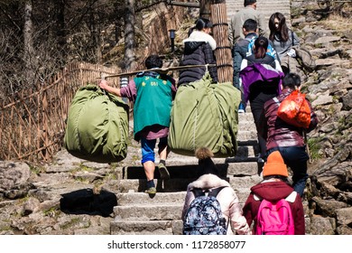 Huangshan, Anhui, China - April 13, 2017: With no roads to the summit of Huangshan, workers have to carry heavy loads, using carrying pole, and walk up thousands of steps to the hotels at the summit.