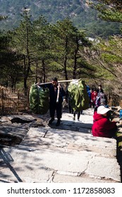 Huangshan, Anhui, China - April 13, 2017: With no roads to the summit of Huangshan, workers have to carry heavy loads, using carrying pole, and walk up thousands of steps to the hotels at the summit.