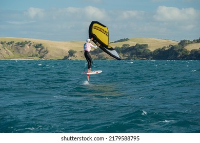Huaraki Gulf, Auckland  New Zealand - 230221: A young man wing foils in the ocean between Great Barrier Island and Auckland, using a hand held inflatable wing and riding a hydrofoil surf board.