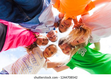 A Huddle Of School Kids Looking Down At Camera,