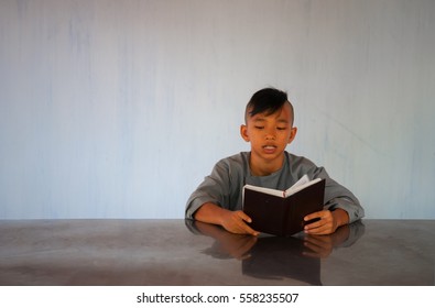 HUE, VIETNAM - JULY 6 2009: Vietnamese Monk Apprentice Reading And Turning Pages From A Holy Book Inside A Convent In Hue.