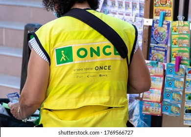 Huelva, Spain - July 4, 2020: View of back of the dressing of a woman selling lottery tickets for helping blind people with the logo of  'Once' organization