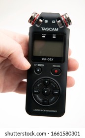 HUETTENBER, GERMANY - FEBRUARY 03, 2020: Male Hand Hold Tascam DR-05X Digital Audio Recorder. Portable Field Recorder On White Desk.