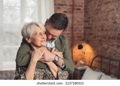 hug between caucasian elderly mother and her middle-aged bearded son medium shot. High quality photo