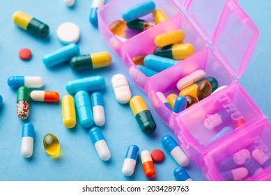 Huge amount of pills on blue background with a box organiser or reminder for taking pills. Prescribed pills for an ill person