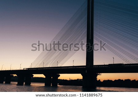 A huge bridge in the background of the sunset, which divides the city into two parts.