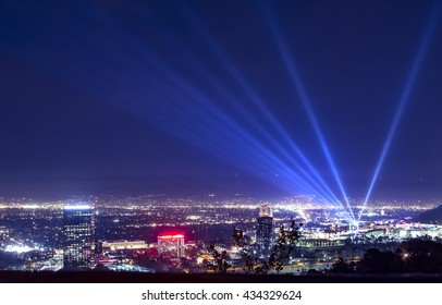 Huge Bright Powerful Spotlight Rays Over The Night Sky Panorama Of Los Angeles City From Hollywood Hills.