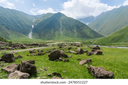Huge brown stones in a river valley among mountains covered with greenery - Powered by Shutterstock