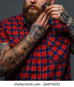 Huge Brutal Man With Tattoo Shawing His Beard With A Razor