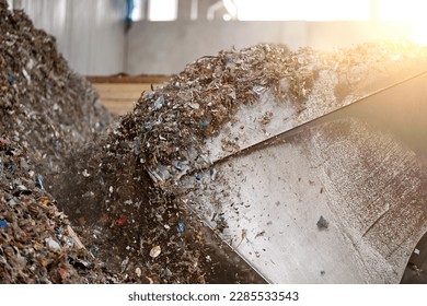 Huge bucket of heavy loader processing pile of refuse-derived fuel (RDF) for combustion. Processing municipal solid waste to energy source. Energy resource recovery with waste-to-energy conversion. - Shutterstock ID 2285533543