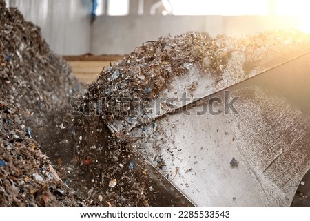 Huge bucket of heavy loader processing pile of refuse-derived fuel (RDF) for combustion. Processing municipal solid waste to energy source. Energy resource recovery with waste-to-energy conversion.