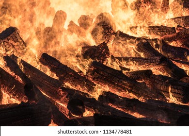 Huge burning bonfire at night. A pyre with burning wood and flames. Heat of burning wooden logs.