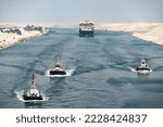 Huge cargo ships with pilot boats navigate by Suez Canal, Egypt. Concept of transportation and logistics 