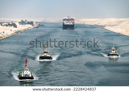 Huge cargo ships with pilot boats navigate by Suez Canal, Egypt. Concept of transportation and logistics 