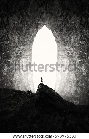 Huge cave entrance with man silhouette on cliff, surreal underground landscape