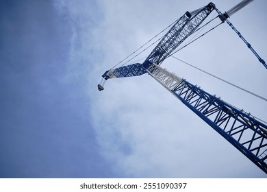 Huge crane bottom up view. Crane boom opposite cloudy sky low angle view. Heavy lifting machinery  - Powered by Shutterstock