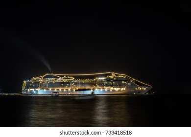 A Huge Cruise Ship At Night Stands At Anchor Glowing With Very Bright Lights