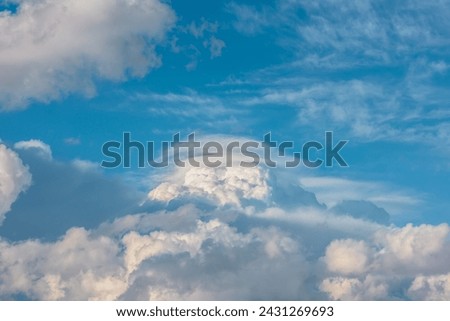 Huge dramatic lenticular cloud on white lush cloudy hill in blue sky. Beautiful cloudscape with big UFO shaped cloud in center. Scenic skyscape with altocumulus clouds. Awesome unusual cloudy skies.