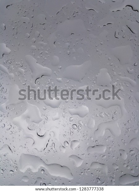 Huge drops of rain on glass, rain drops on clear\
glass roof of a car
