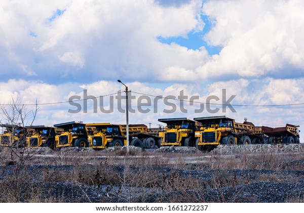 Huge dump trucks parked\
near quarry