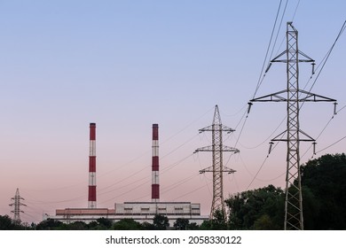 Huge electric poles, electric lines and pipes of thermoelectric power station against sunset in Kiev, Ukraine
