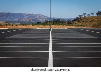 Huge Empty Parking Lot Perfectly Divided In Half With Mountains In The Background