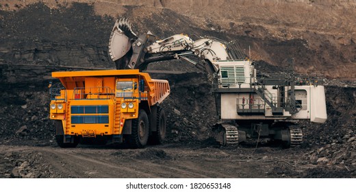 A Huge Excavator Loads Rock Formation Into The Back Of A Heavy Mining Dump Truck. Open Pit Coal Mining.