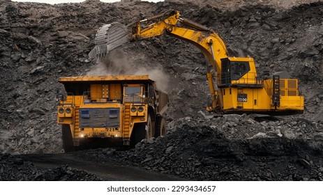 A huge excavator loads rock formation into the back of a heavy mining dump truck. Open pit coal mining. - Shutterstock ID 2293434657