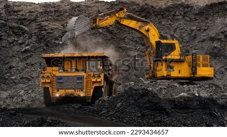 A huge excavator loads rock formation into the back of a heavy mining dump truck. Open pit coal mining.