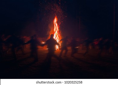 Huge fire at night and young people around. Pagan festival of Walpurgis night: bonfires, dancing wildly, demons, witches. 