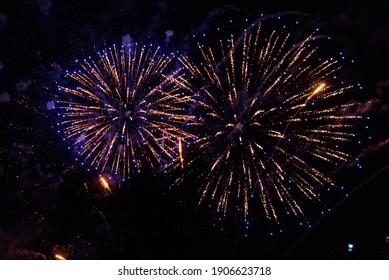 Huge fireworks explosions with Violet and golden colors over a party in the park. In front of the black night sky - Shutterstock ID 1906623718