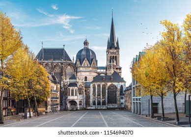 Huge gothic cathedral in Aachen Germany during autumn with yellow trees at Katschhof against blue sky in the background