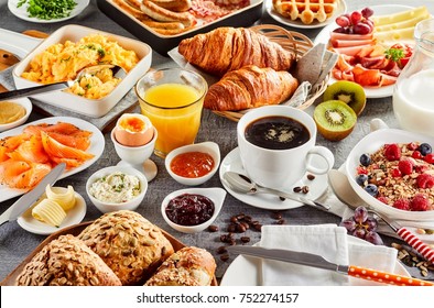 Huge healthy breakfast spread on a table with coffee, orange juice, fruit, muesli, smoked salmon, egg, croissants, meat and cheese - Shutterstock ID 752274157