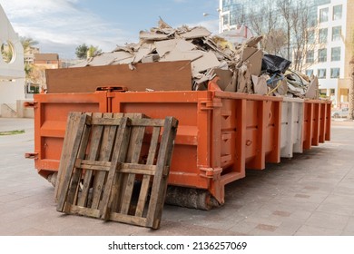 huge heap on metal Big  Overloaded dumpster waste container filled with construction waste, drywall and other rubble near a construction site. - Shutterstock ID 2136257069