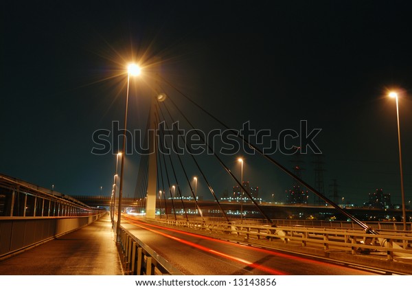 huge highway structure at suspension support by\
night in Tokyo, Japan with red car traces and walking man\'s\
silhouette ahead